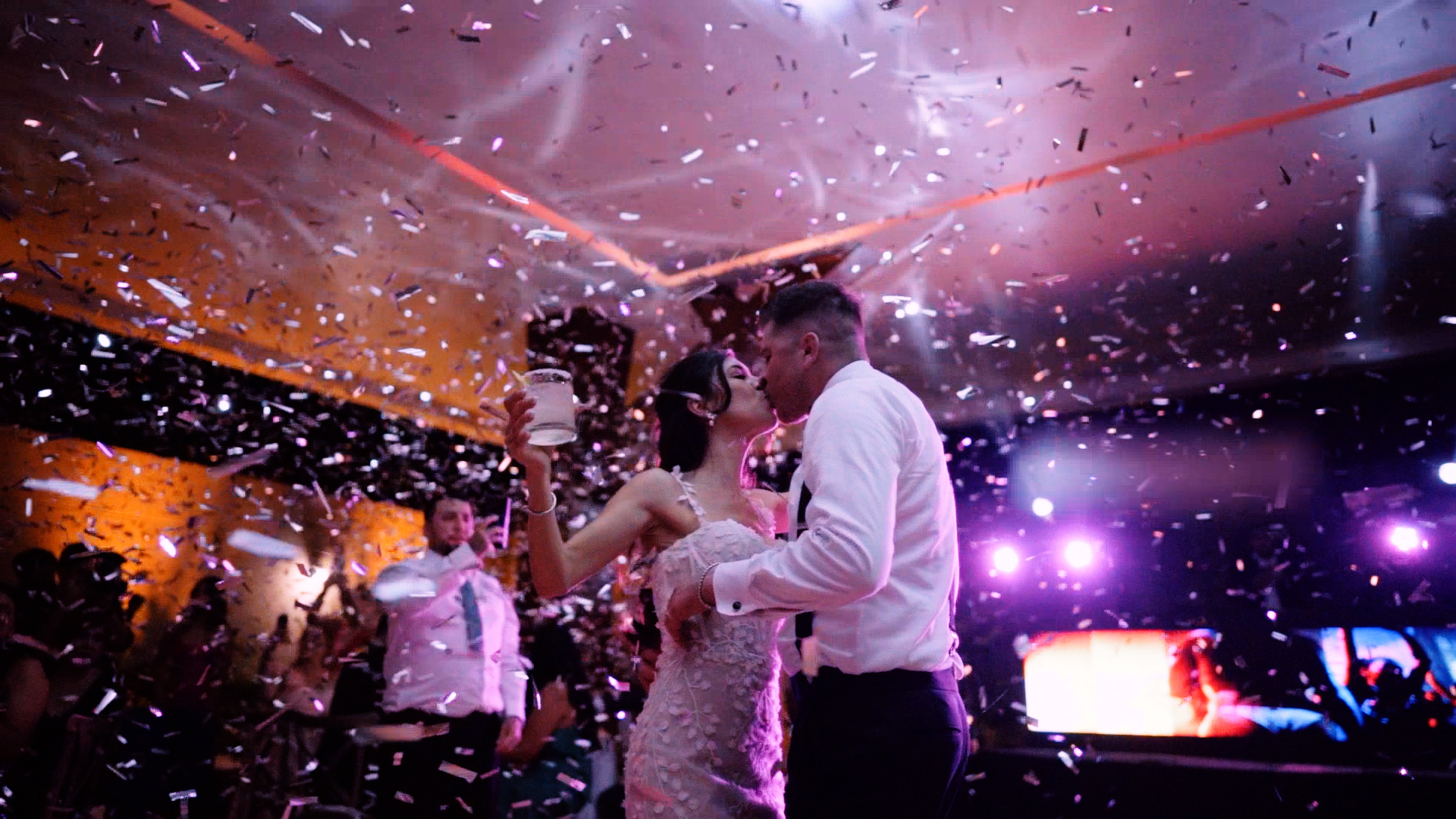 Couple kissing in a wedding party while confetti falls down